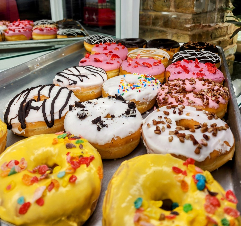 Gourmet donuts on trays with colorful glazes and toppings